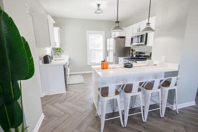 kitchen featuring appliances with stainless steel finishes, pendant lighting, sink, white cabinets, and kitchen peninsula