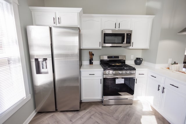 kitchen with stainless steel appliances, a wealth of natural light, and white cabinetry