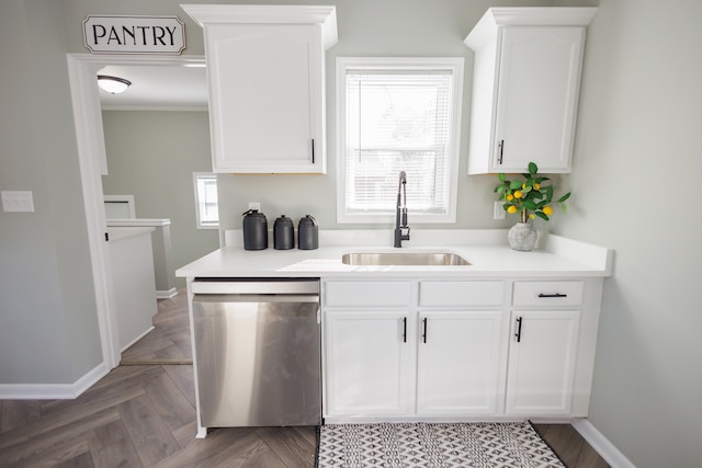 kitchen with dishwasher, sink, parquet flooring, and white cabinets