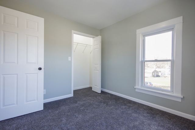 unfurnished bedroom with a closet and dark carpet