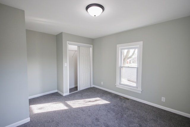 unfurnished bedroom featuring dark colored carpet and a closet