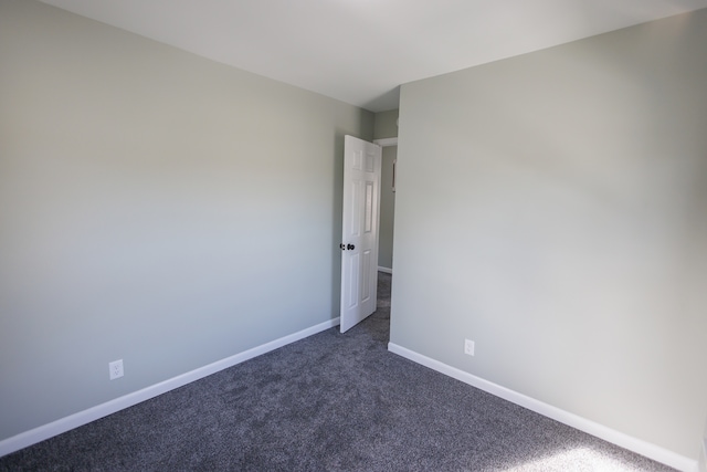 spare room with dark colored carpet