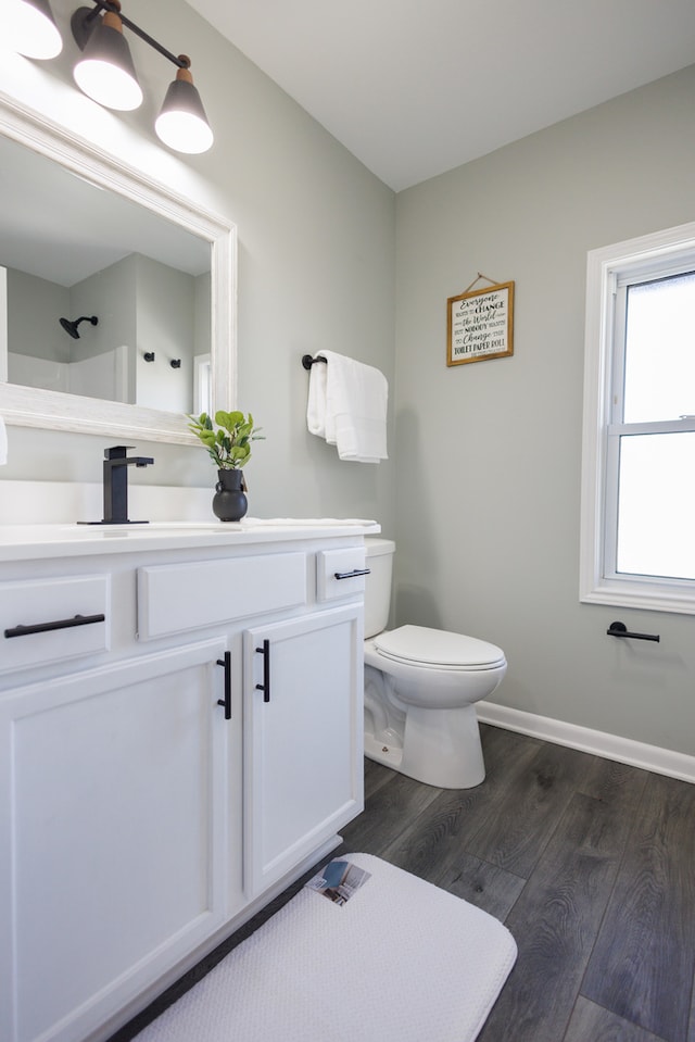 bathroom featuring toilet, vanity, hardwood / wood-style floors, and walk in shower