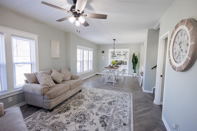 living room featuring plenty of natural light, dark parquet flooring, and ceiling fan