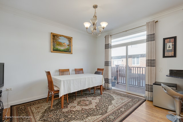 dining room with a chandelier, light wood-type flooring, and crown molding