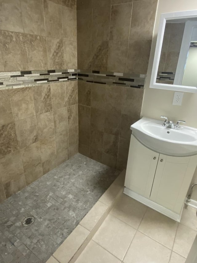 bathroom featuring tile patterned flooring, a tile shower, and vanity