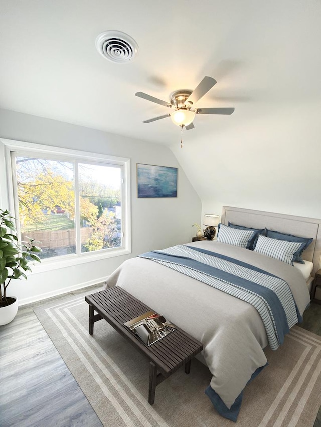 bedroom with ceiling fan, light hardwood / wood-style flooring, and lofted ceiling