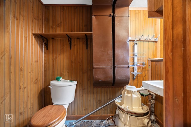 bathroom featuring wooden walls and toilet