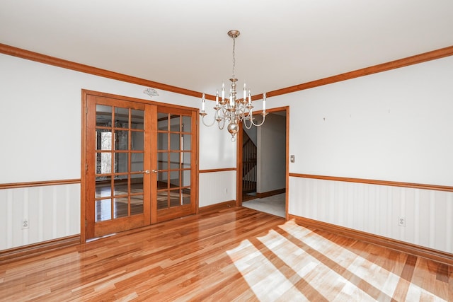 unfurnished dining area with a notable chandelier, hardwood / wood-style flooring, ornamental molding, and french doors