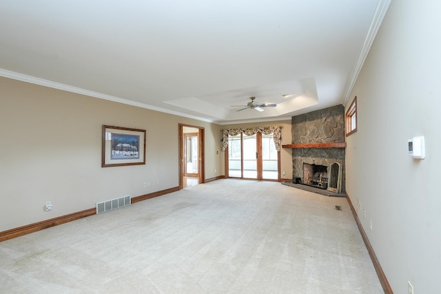 unfurnished living room featuring a fireplace, carpet flooring, ceiling fan, a tray ceiling, and crown molding