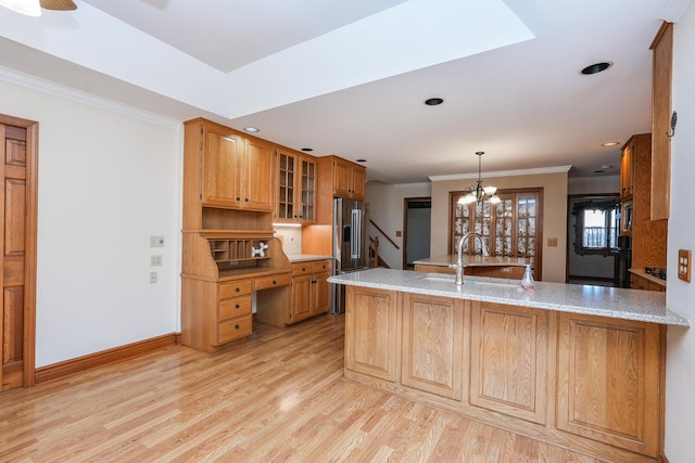 kitchen with sink, crown molding, light stone counters, light hardwood / wood-style floors, and kitchen peninsula