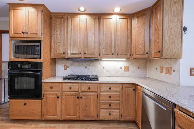 kitchen with light hardwood / wood-style flooring, decorative backsplash, light stone counters, and black appliances