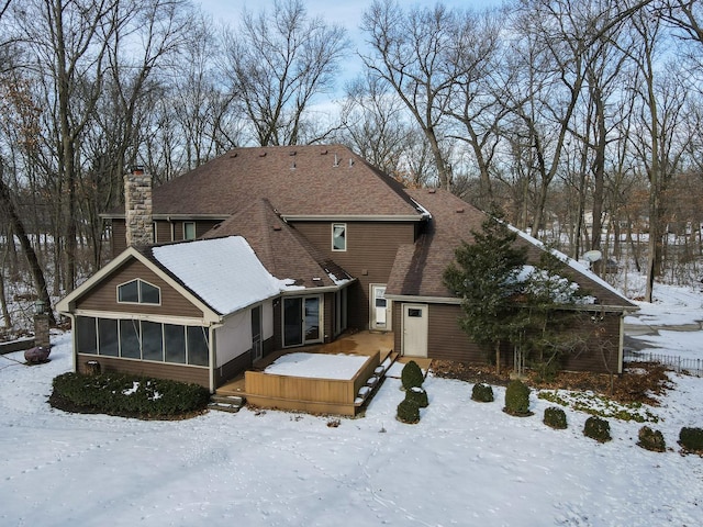 snow covered house featuring a sunroom