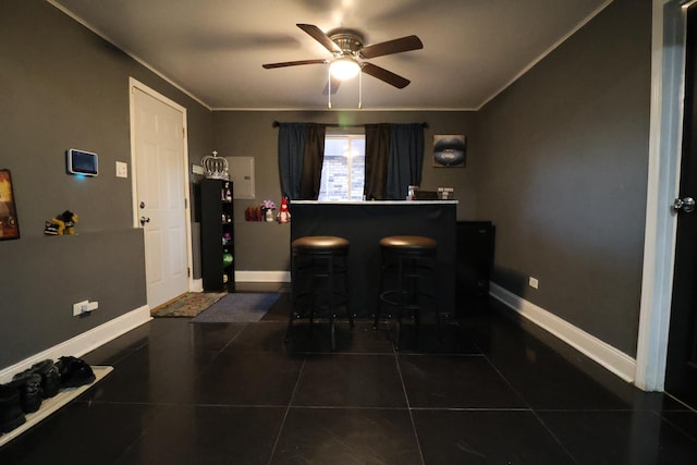 dining area featuring dark tile patterned flooring, bar, crown molding, and ceiling fan