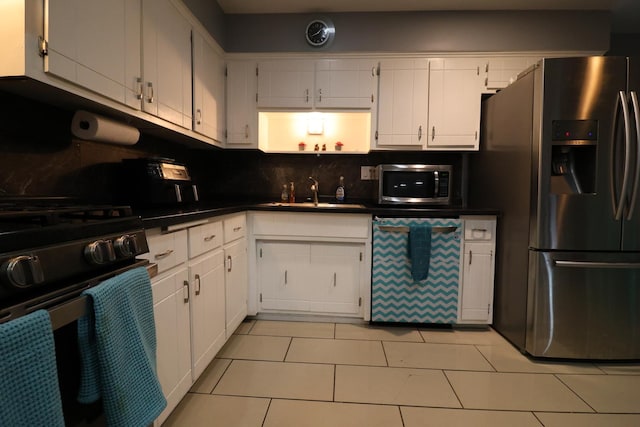 kitchen featuring light tile patterned flooring, appliances with stainless steel finishes, white cabinetry, and sink