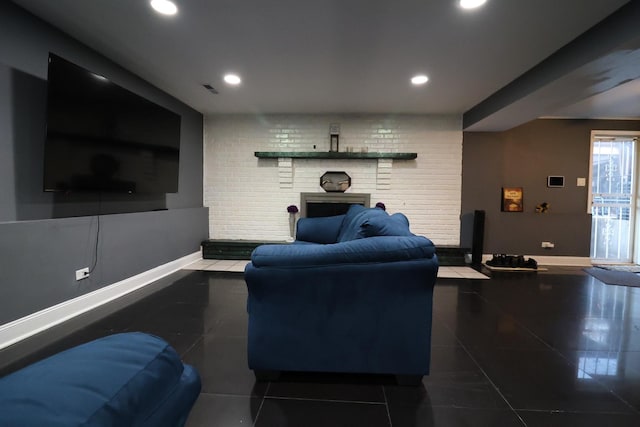 living room with a fireplace, dark tile patterned floors, and brick wall