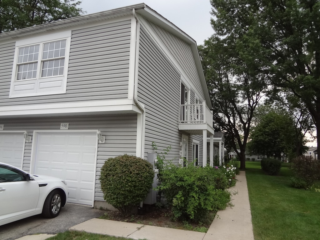 view of home's exterior featuring a garage, a yard, and a balcony