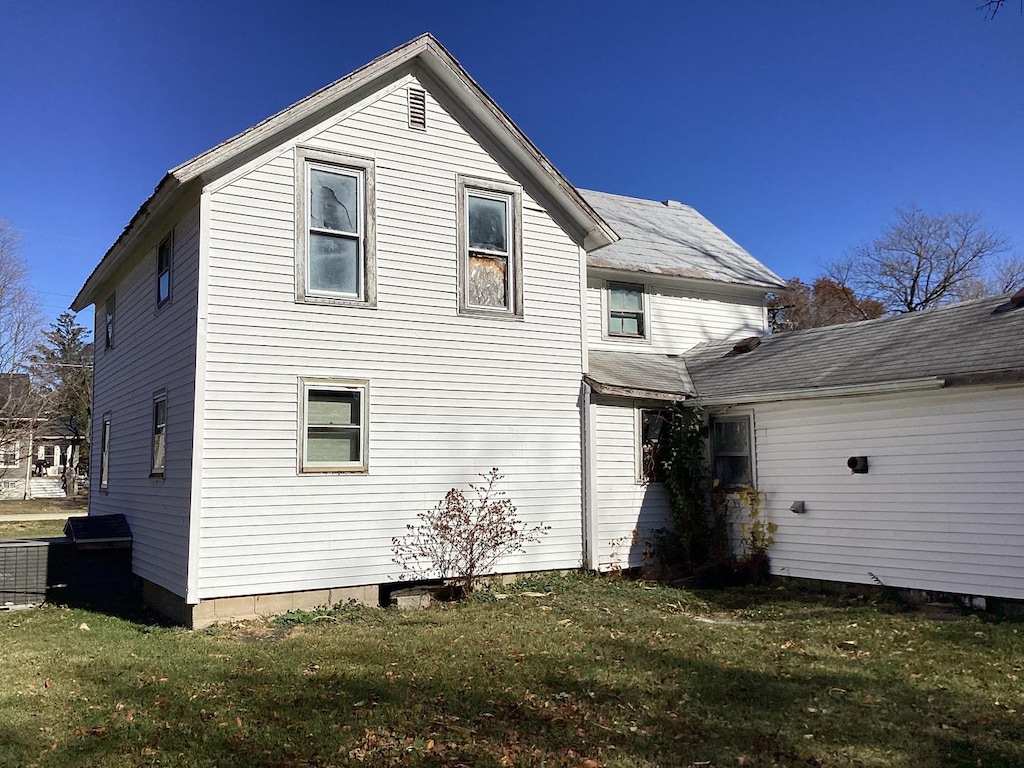 back of property with central air condition unit and a lawn