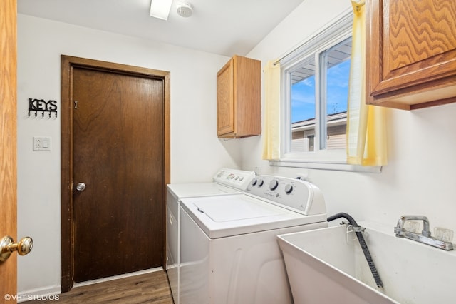 clothes washing area with dark hardwood / wood-style floors, cabinets, independent washer and dryer, and sink