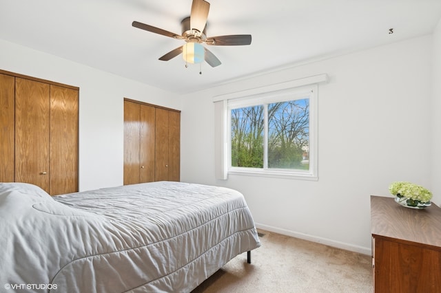 carpeted bedroom featuring ceiling fan and multiple closets