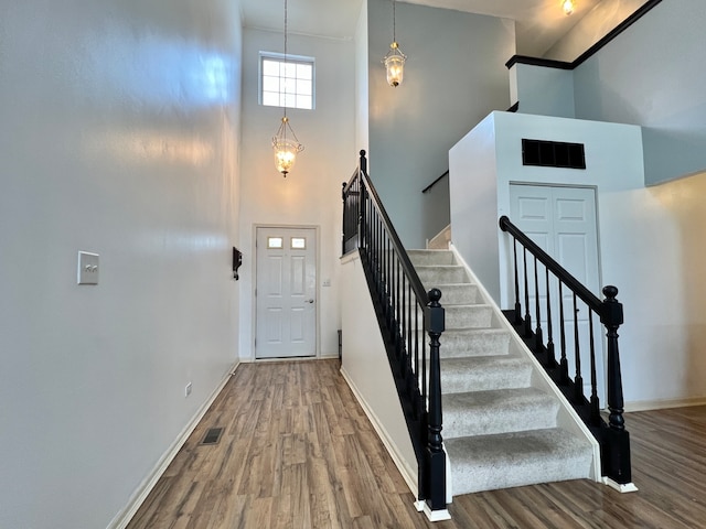 staircase with hardwood / wood-style floors and a high ceiling