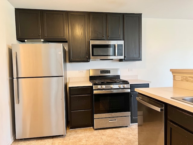 kitchen with stainless steel appliances, light tile patterned flooring, and dark brown cabinetry