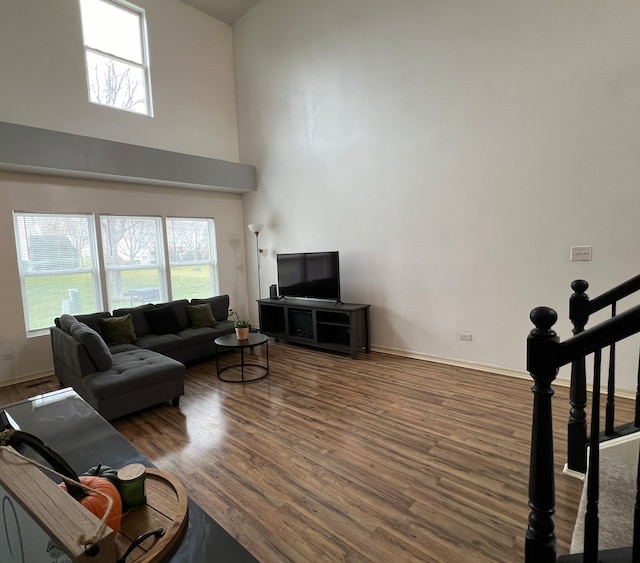 living room featuring a towering ceiling and dark wood-type flooring