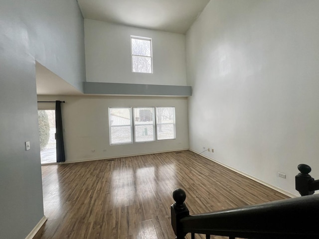 spare room with a towering ceiling, hardwood / wood-style floors, and a wealth of natural light