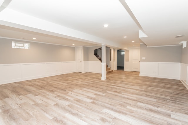 basement with light wood-type flooring and ornamental molding