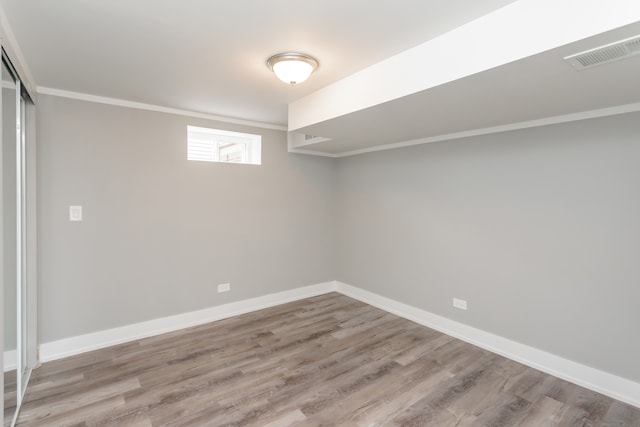 basement featuring ornamental molding and light hardwood / wood-style flooring