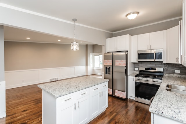 kitchen featuring white cabinetry, appliances with stainless steel finishes, decorative light fixtures, dark wood-type flooring, and a center island