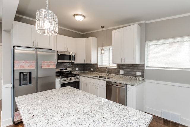 kitchen with hanging light fixtures, white cabinetry, sink, and appliances with stainless steel finishes