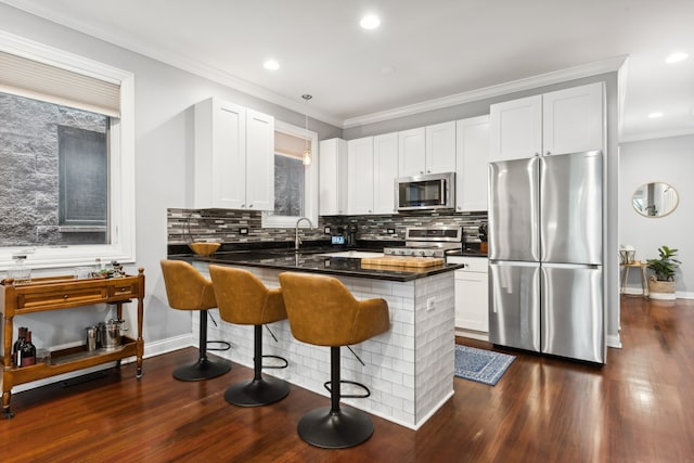 kitchen featuring white cabinets, a kitchen breakfast bar, kitchen peninsula, and appliances with stainless steel finishes