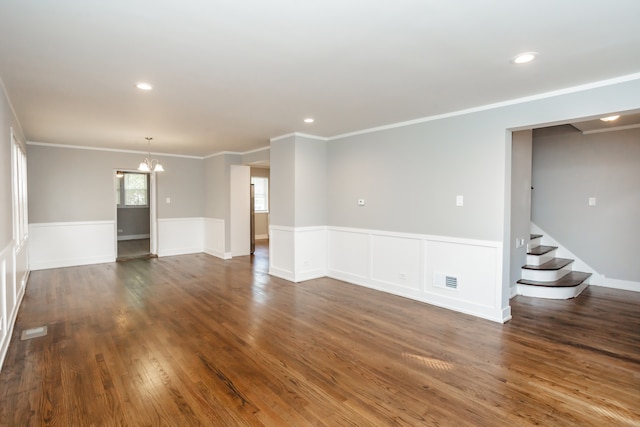 empty room featuring dark hardwood / wood-style floors, a chandelier, and crown molding