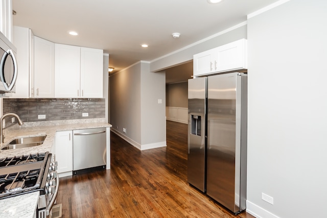 kitchen with stainless steel appliances, dark hardwood / wood-style flooring, light stone countertops, sink, and white cabinets