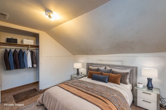 bedroom featuring a closet, vaulted ceiling, and dark colored carpet