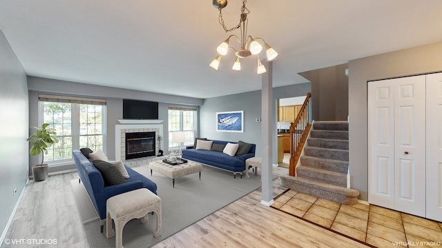 living room with a chandelier, a tile fireplace, and light wood-type flooring