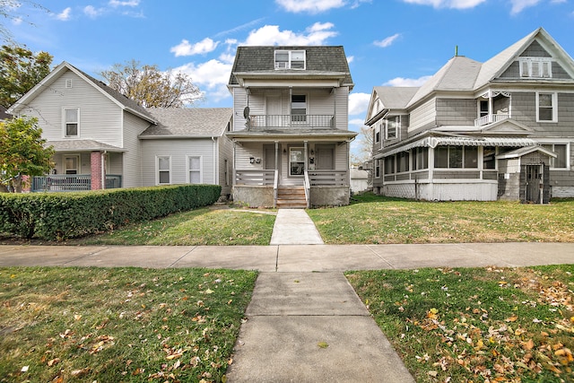 view of property with a front lawn, a balcony, and a sunroom