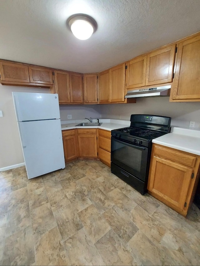 kitchen with black gas stove, a textured ceiling, white fridge, and sink