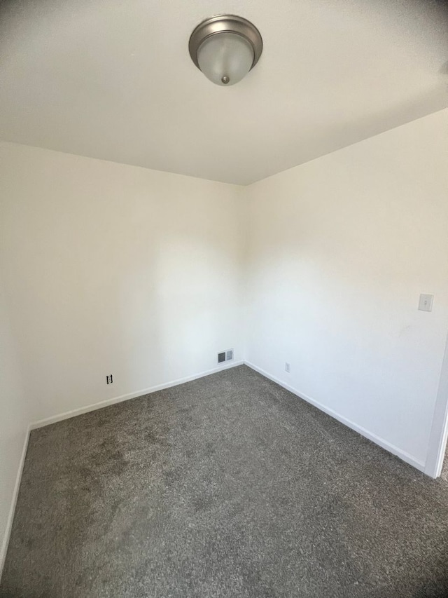 spare room featuring dark colored carpet