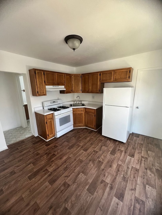 kitchen with dark hardwood / wood-style floors, white appliances, and sink