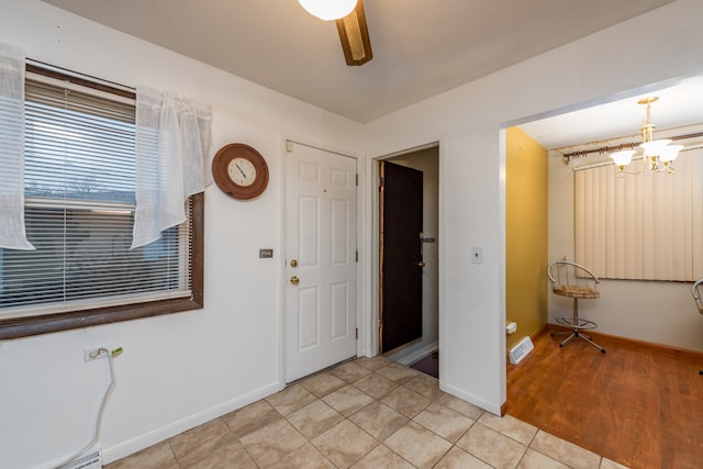 foyer with ceiling fan with notable chandelier and light wood-type flooring