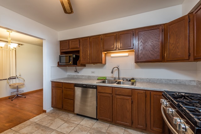 kitchen featuring stainless steel appliances, light hardwood / wood-style floors, a chandelier, sink, and pendant lighting