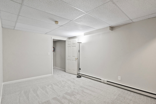 basement with a baseboard radiator, a drop ceiling, and carpet floors