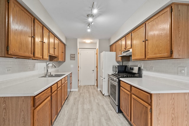 kitchen with decorative backsplash, appliances with stainless steel finishes, sink, and light hardwood / wood-style floors