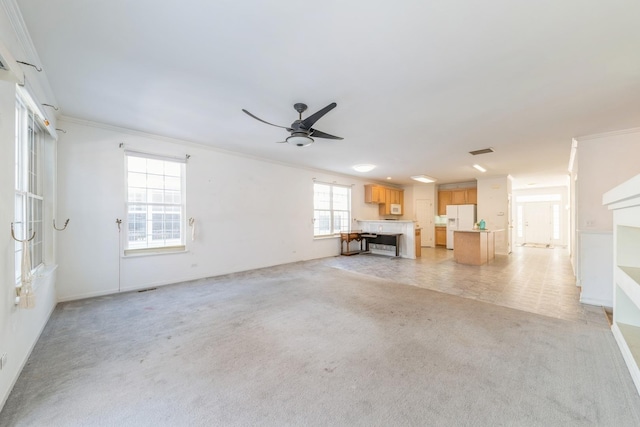 unfurnished living room with ornamental molding, light colored carpet, and ceiling fan