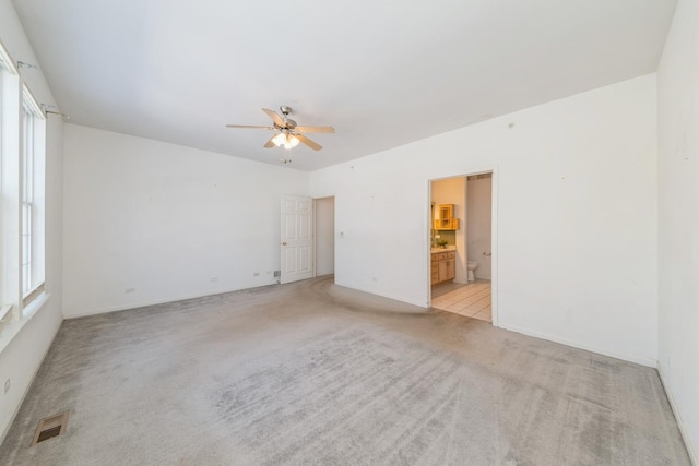 carpeted spare room featuring plenty of natural light and ceiling fan