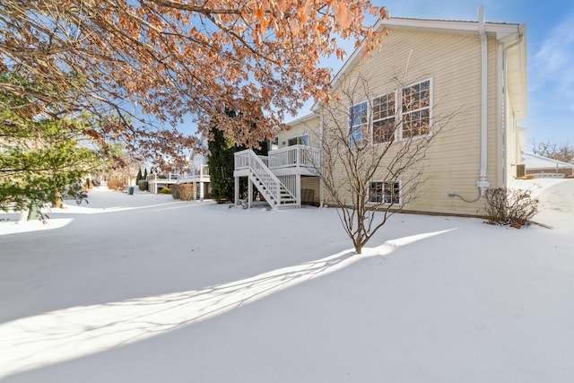 snow covered back of property with a wooden deck