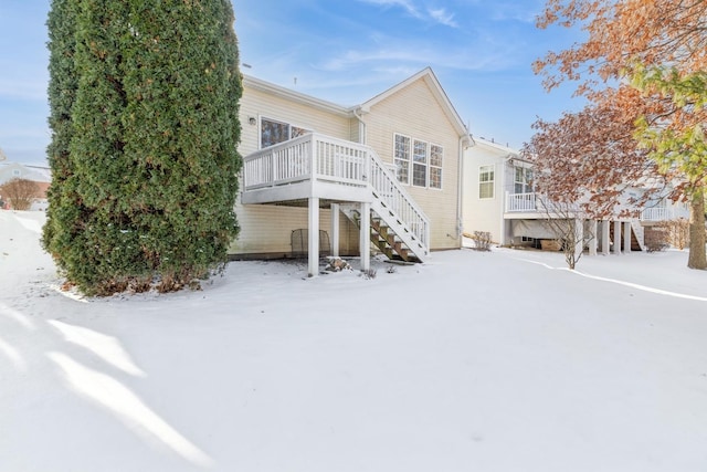 snow covered rear of property with a wooden deck