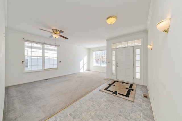 foyer with light carpet, ornamental molding, and ceiling fan